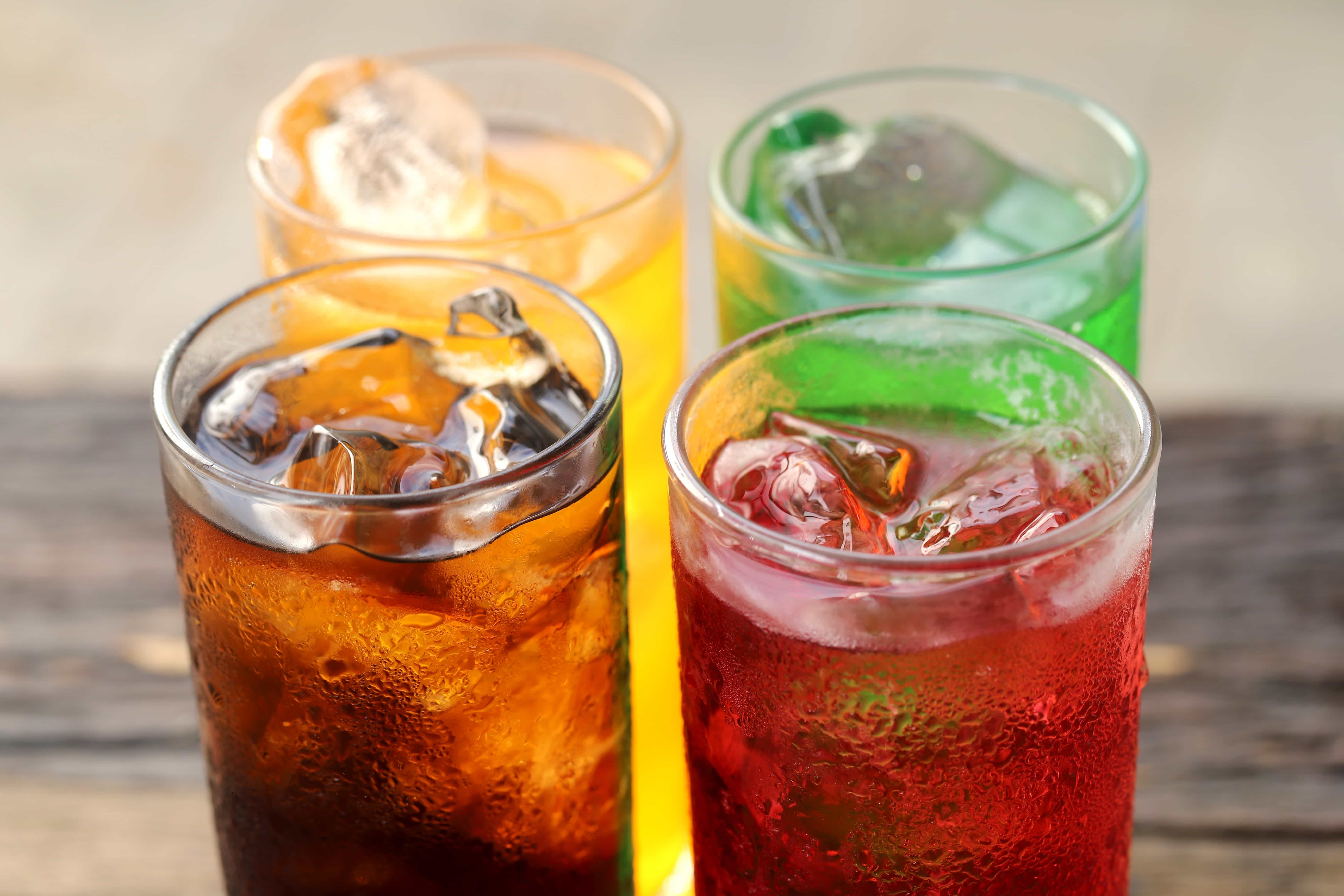 four glasses with different soda drinks